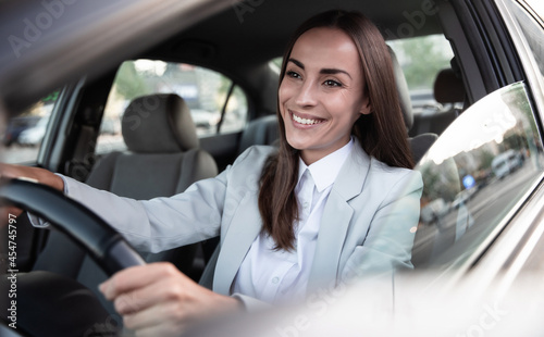 Beautiful happy successful businesswoman is driving a new modern car in good mood. Portrait cute female driver steering car with safety belt © My Ocean studio