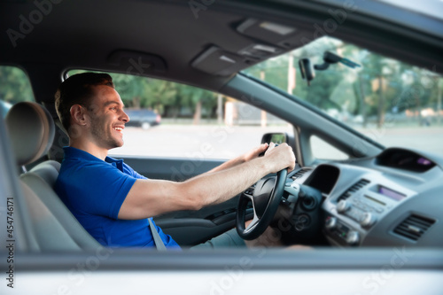 Close up photo of young handsome successful man is driving his modern car