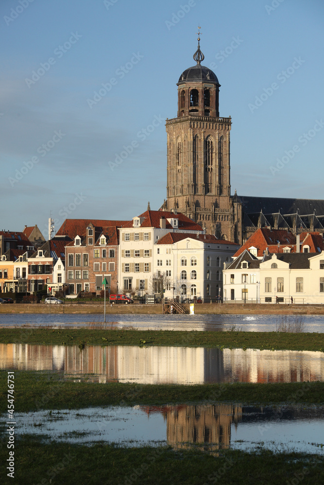 The facades of beautiful old buildings and the tower of the Great Church in the city of Deventer, The Netherlands, with reflection in the river IJssel