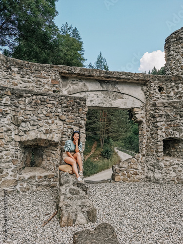 Portrait of stylish young millennial female sitting in front of medieval ruin. photo