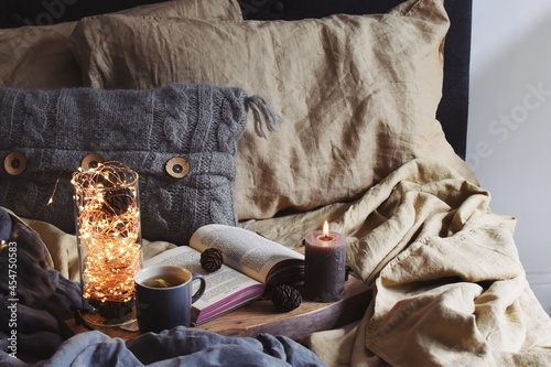 Cozy home and hygge lifestyle. Candles, book and cup of tea