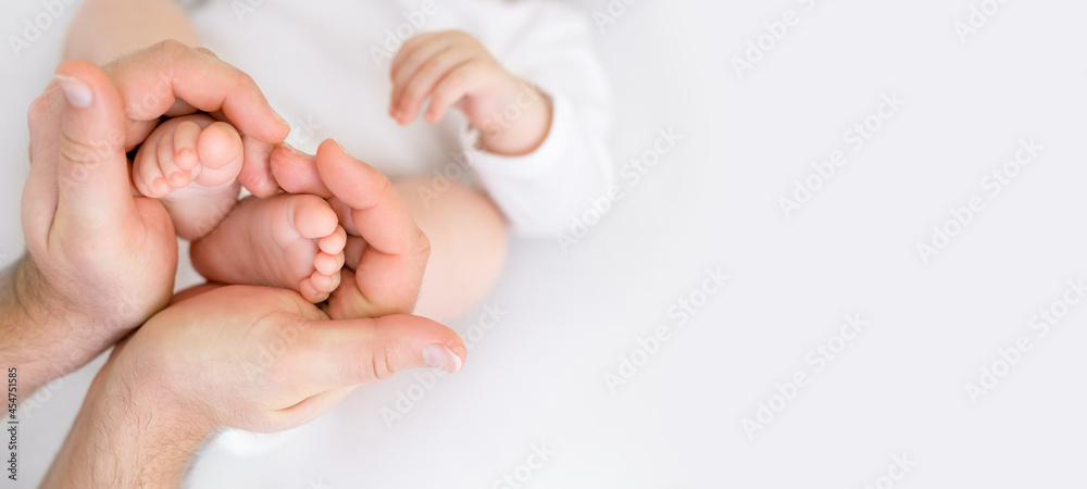 Small children's legs in the shape of a heart in dad's strong male hands. Tenderness and love from birth. Care and raising of children health. banner - obrazy, fototapety, plakaty 