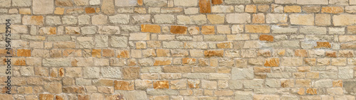 Alte grobe Panorama Steinwand aus verschiedenen viereckigen Natursteinen in beige, ocker und braun