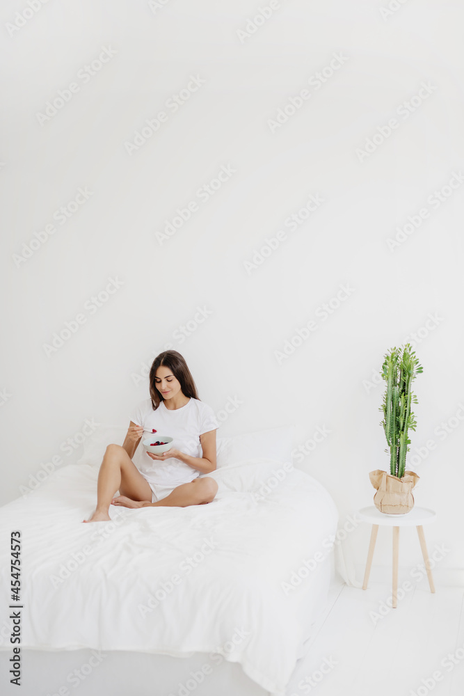 Adorable woman having breakfast sitting on her bed at home. Adorable woman having breakfast sitting on her bed at home.