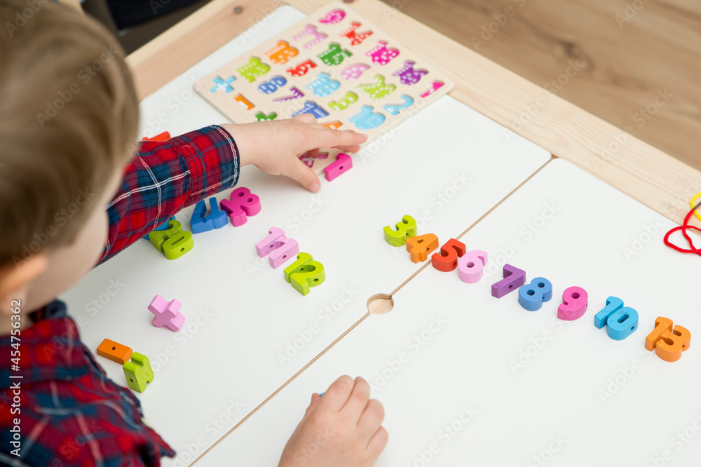 kid learning numbers through game. Sensory activity with wooden numbers ...