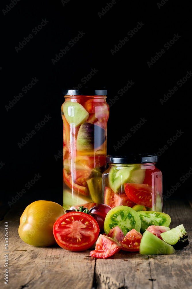 Canned tomatoes on a glass jar on a black background