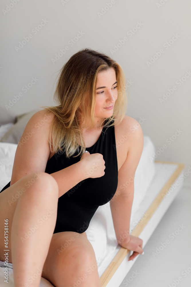 Fototapeta premium body positive. A woman in black underwear poses on a modern white interior 