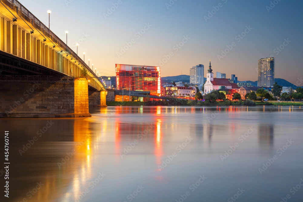 Linz, Austria. Cityscape image of riverside Linz, Austria at summer sunset with reflection of the city lights in Danube river.