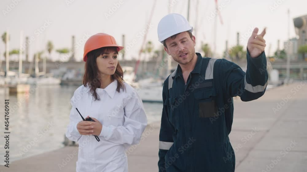 Port worker instructing new female employee in marina Port worker instructing new female employee in marina