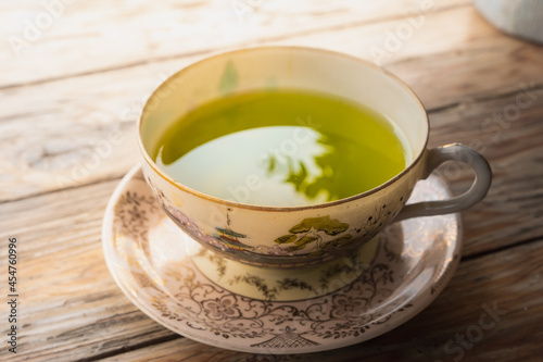 Green tea in a porcelain cup resting on an old wooden floor gives a warm feeling.tea cup with Chinese culture pattern
