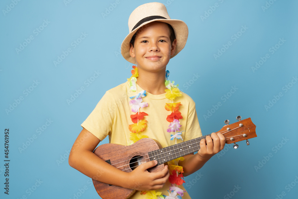 Smiling caucasian boy is playing the guitar - isolated on blue background Smiling caucasian boy is playing the guitar - isolated on blue background