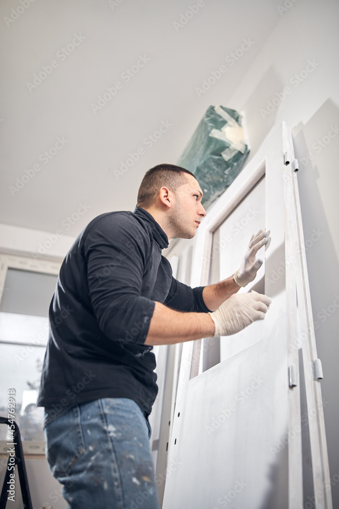 Young adult man painting on a DIY budget renovation of his new home apartment. Young adult man painting on a DIY budget renovation of his new home apartment.