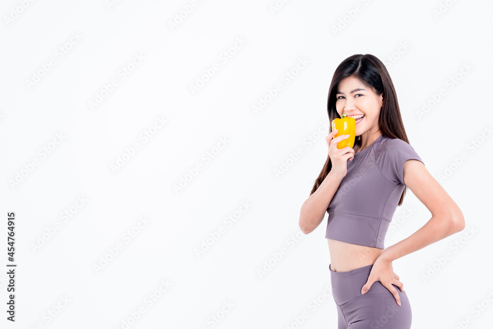 Portrait images of Asian attractive woman is good shape, holding and eating a yellow vegetable, bell pepper, On white background, concept to weight loss woman and health care concept. Portrait images of Asian attractive woman is good shape, holding and eating a yellow vegetable, bell pepper, On white background, concept to weight loss woman and health care concept.