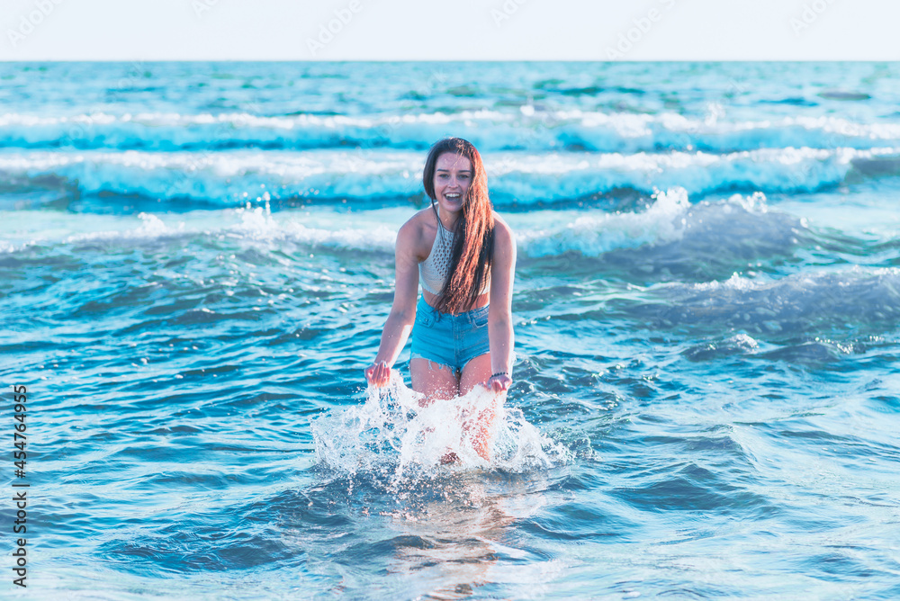 Young woman playing in the sea.woman make in sea water splash.Cheerful young woman having fun on the summer beach.