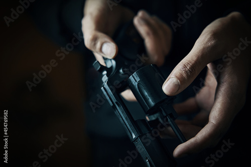 Reloading gun close-up. Men's hands check for bullets in revolver barrel. Person prepares for shots. Firearm for defense or attack.