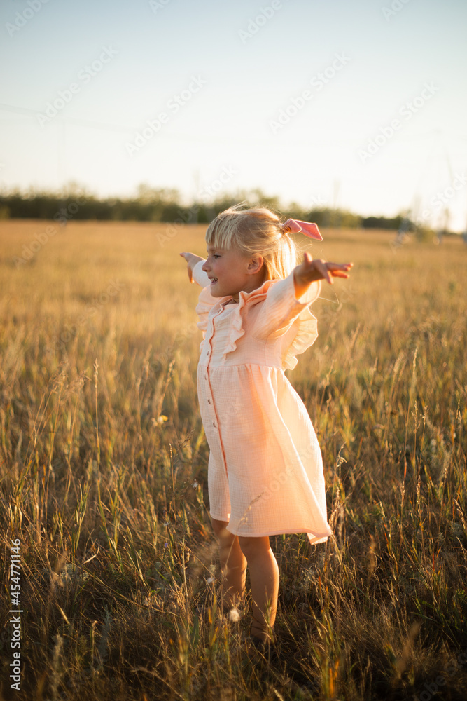 A girl with long hair plays and runs in the rays of the setting sun in a pink dress A girl with long hair plays and runs in the rays of the setting sun in a pink dress