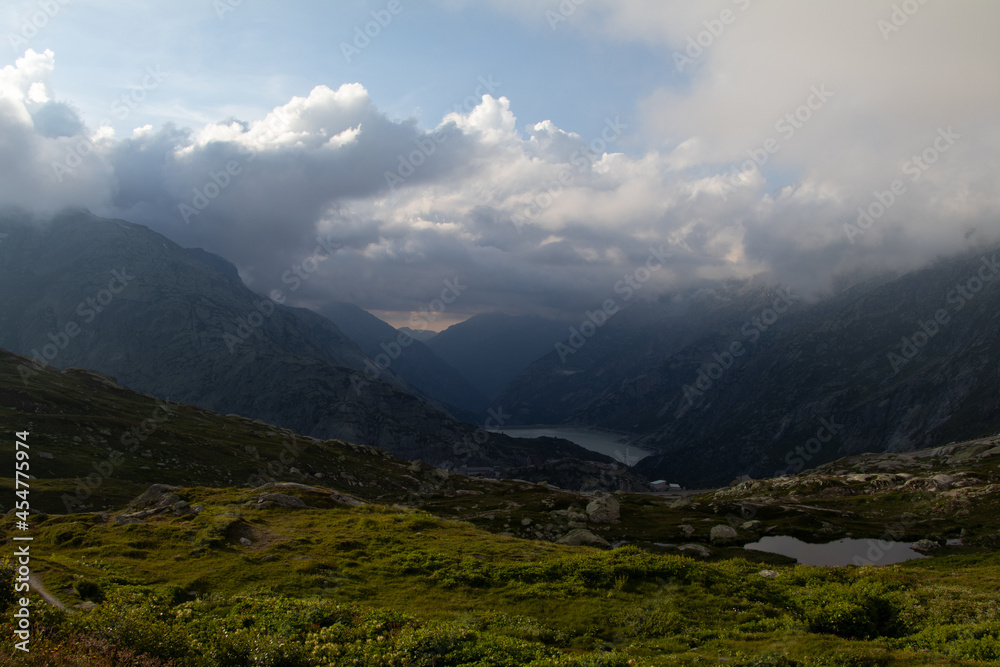 Amazing Landscape in the hearth of Canton Bernese in Switzerland. Drive on the Grimselpass. Epic scenery with the clouds and fog. Wonderful sun rays through the clouds and later an amazing sunset.