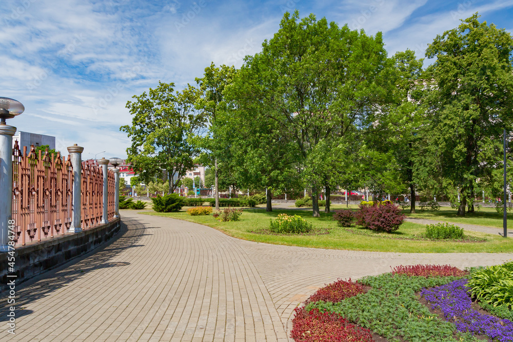 Obraz premium Green city park with walking paths, trees and flower beds