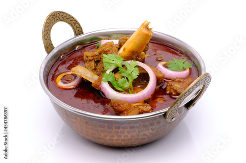 Indian style mutton curry in a copper brass bowl on white background photo