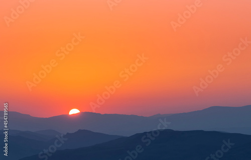 Bright summer sunset over the mountais silhouette. 