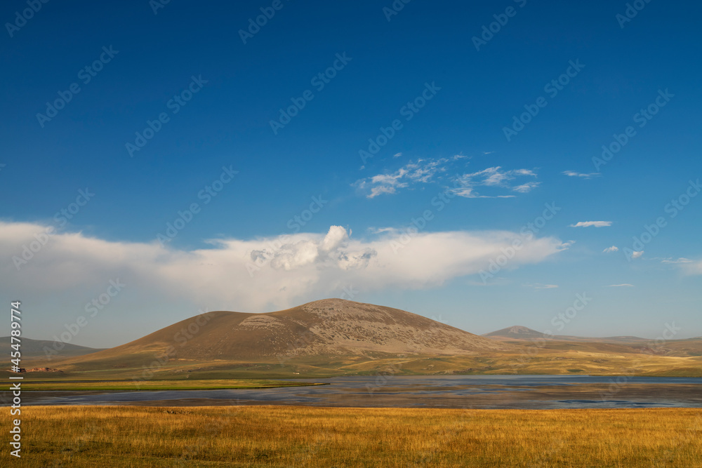 Beautiful landscape. Yellow hills mountains and small lake and blue sky.