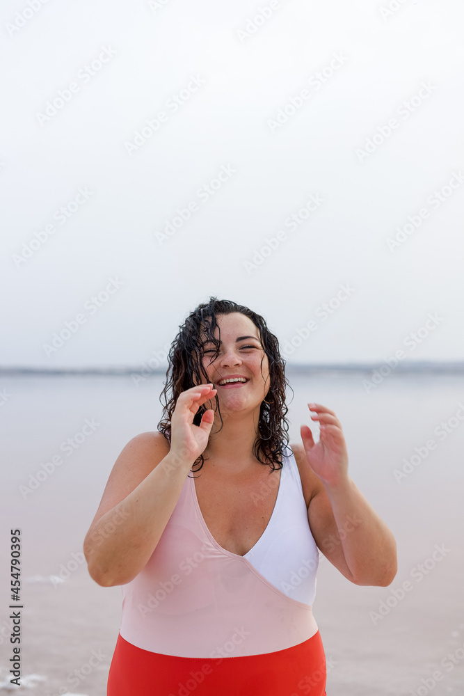 Delighted curvy woman in swimsuit on shore of lake Delighted curvy woman in swimsuit on shore of lake