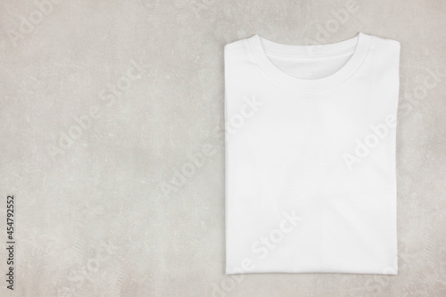 White womens folded cotton tshirt mockup on gray concrete background. Design t shirt template, print presentation mock up. Top view flat lay. 