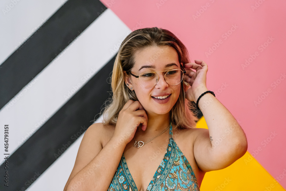blonde girl with glasses posing with colorful background