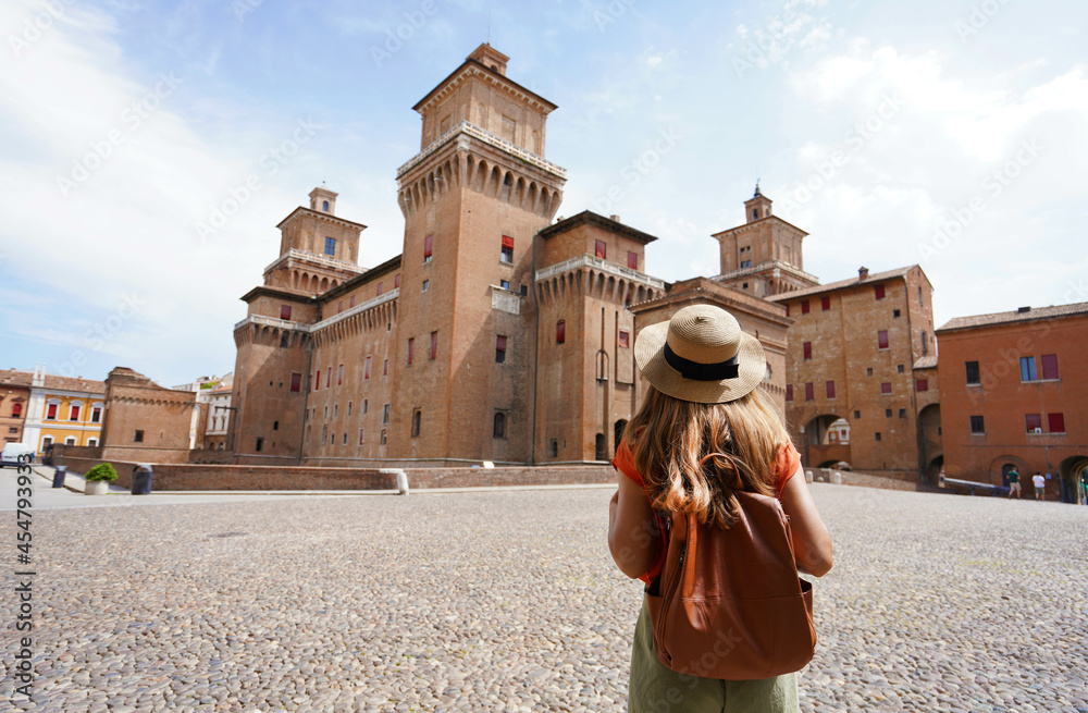 Travel in Italy. Rear view of traveler girl walking towards Este Castle (Castello Estense) of Ferrara, Italy. - obrazy, fototapety, plakaty 