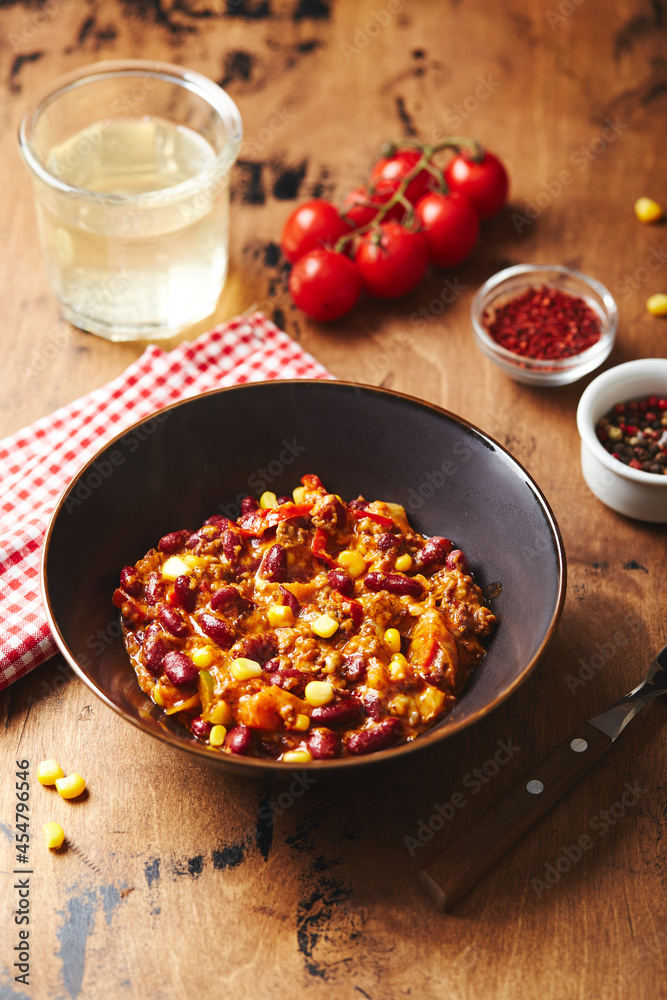 Φωτογραφία Chili Con Carne with ground beef, beans and corn in dark bowl on wooden background