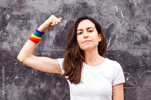 Young lesbian woman showing biceps with rainbow armband. LGBT power photo