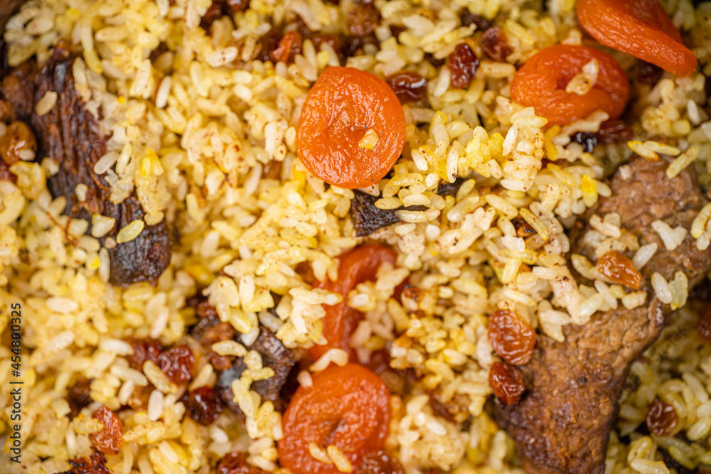 Pilaf with meat, dried apricots and raisins as background Pilaf with meat, dried apricots and raisins as background