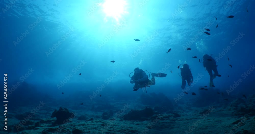 scuba divers coming down descending scenery underwater sun beams and rays sun shine silhouette scenery