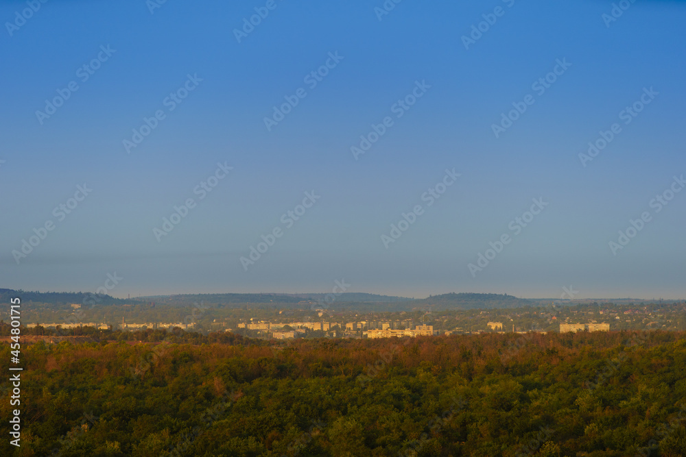 Panoramic view of a small town in eastern Europe in the morning or evening light, the city is surrounded by hills and forests.