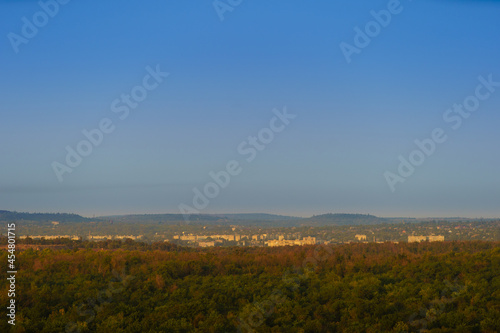 Panoramic view of a small town in eastern Europe in the morning or evening light, the city is surrounded by hills and forests.