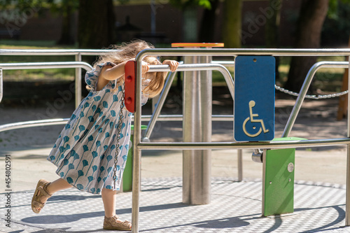 A girl playing on a merry-go-round for the disabled.