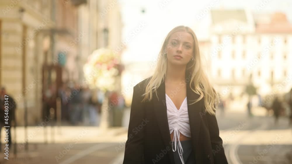 Closeup of beautiful young blond girl with long hair walking down the street. Portrait of gorgeous girl in the city centre. Slow motion. High quality 4k footage Closeup of beautiful young blond girl with long hair walking down the street. Portrait of gorgeous girl in the city centre. Slow motion. High quality 4k footage