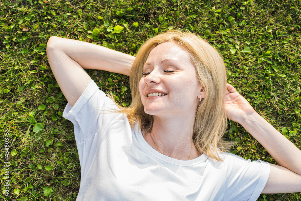 A beautiful and attractive Caucasian woman lying on the grass in a meadow. A beautiful and attractive Caucasian woman lying on the grass in a meadow.