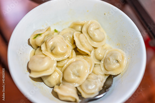 Closeup macro of traditional Russian dumplings pelmeni with meat filling or cheese or potato and bacon stuffing in bowl