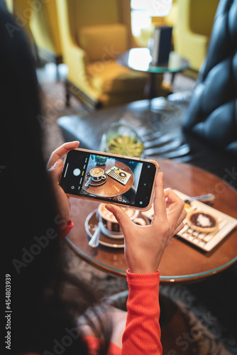 Woman Taking a Photo on her Phone of Coffee in a Coffee Shop