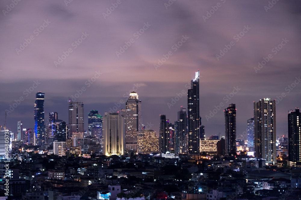 A city landscape at night view in Bangkok, metropolitan area of Thailand with the high rise modern building and lighting illumination over the sky 