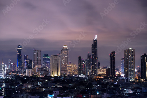 A city landscape at night view in Bangkok, metropolitan area of Thailand with the high rise modern building and lighting illumination over the sky 