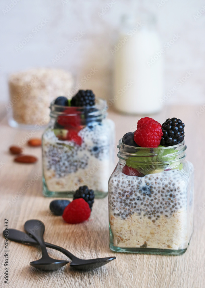 Healthy overnight oatmeal and chia seed pudding with milk and red berries fruit in a jar on wooden table Healthy overnight oatmeal and chia seed pudding with milk and red berries fruit in a jar on wooden table