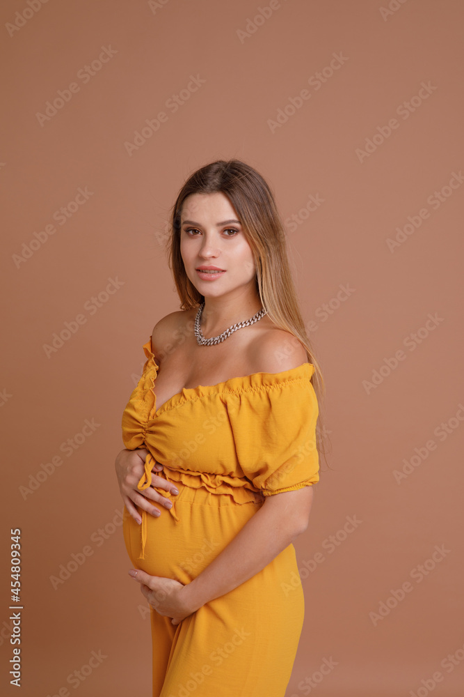 Beautiful pregnant young woman in studio on beige background Beautiful pregnant young woman in studio on beige background