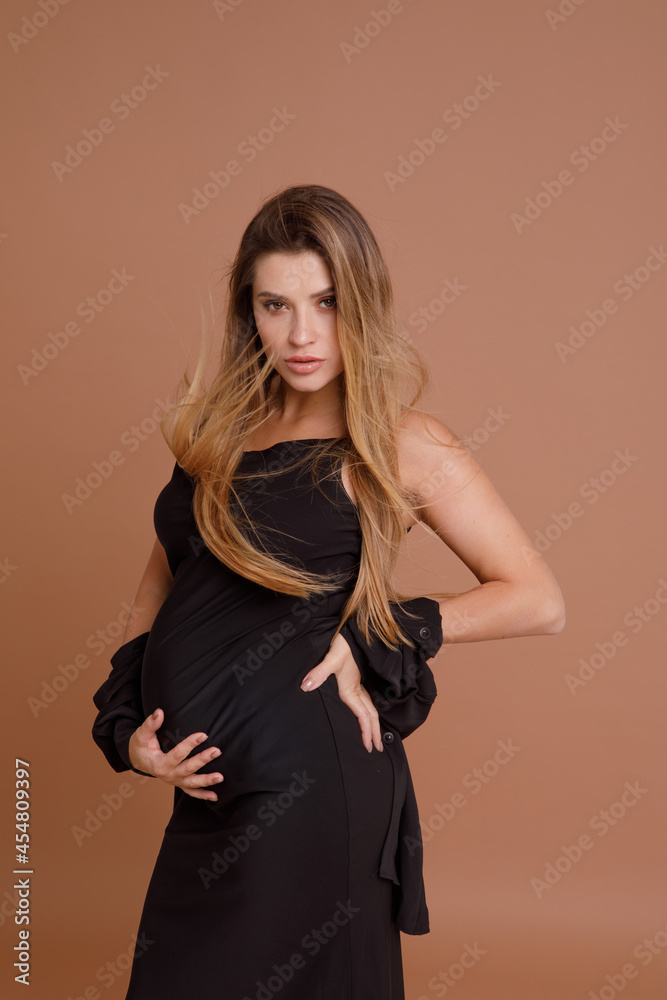Beautiful pregnant young woman in studio on beige background Beautiful pregnant young woman in studio on beige background