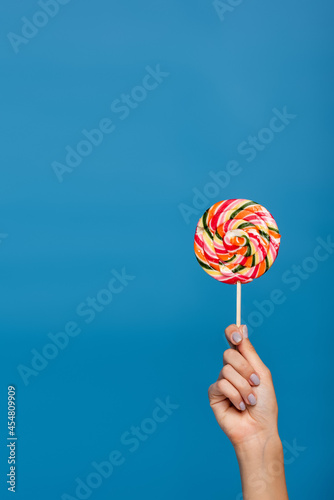 cropped view of woman holding sweet lollipop isolated on blue.