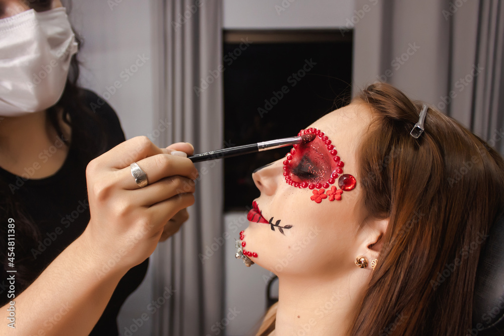 Makeup artist adding glitter on the eyelids of a young girl, Day of the