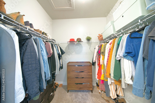 Small space walk-in closet with hanging men and women clothes