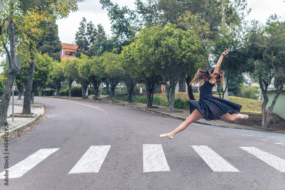 Ballet dancer with pointe shoes doing an acrobatic turn in the street on a pedestrian crossing