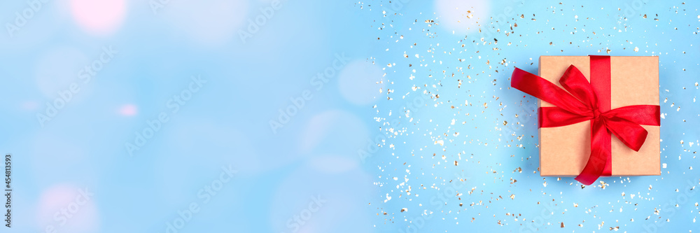 Festive banner with gift box on ligth blue background with bokeh lights around with copy space. Flat lay style for Christmas, New Year, birthday celebration or holidays sale concept Festive banner with gift box on ligth blue background with bokeh lights around with copy space. Flat lay style for Christmas, New Year, birthday celebration or holidays sale concept